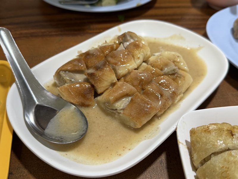 ขนมปังซุปหมูอบในจานขาว ราดน้ำซุปข้น มีช้อนวางข้างจาน