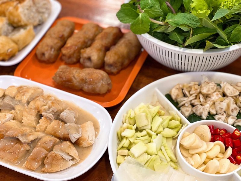 จานแหนมเนืองย่างกับผักสด ผลไม้หั่น และกระเทียม วางคู่ขนมปังซุปหมูอบ