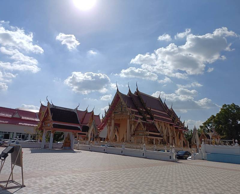 อุโบสถหลังคาซ้อนชั้นบนลานกว้าง ท้องฟ้ามีเมฆขาว